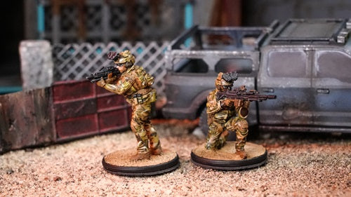 2 Green Beret force miniatures shown in a post apocalyptic setting, with a truck and dilapidated house behind them.