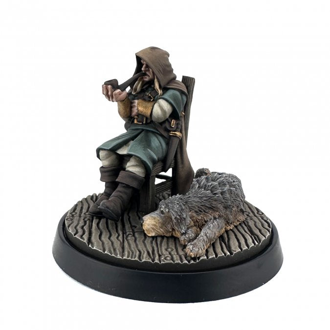 Statue of a character in fantasy attire with a hound on a white background. Reaper Miniatures Mysterious Stranger and hound painted