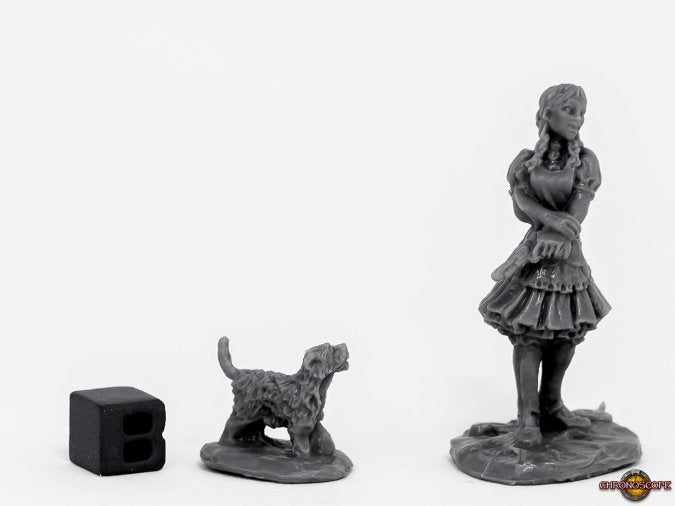 Three gray figurines of a woman, a dog, and a small object on a white background. Wild West OZ Dorothy from Reaper Miniatures, unpainted,.