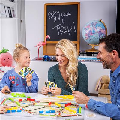 Ticket to Ride: First Journey Board Game being played by a family sitting at a table. Mom, dad, and child hold cards in their hand as they are having fun playing the game